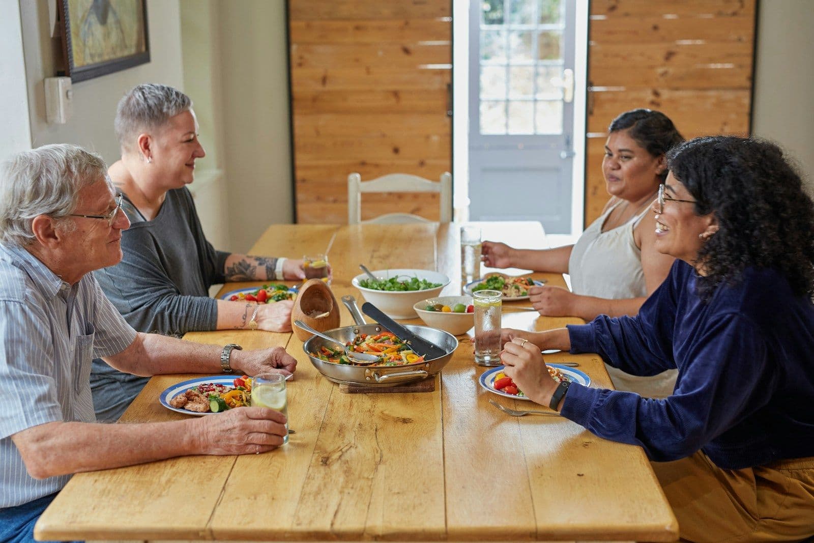 Friends and family sharing dinner around a wooden table