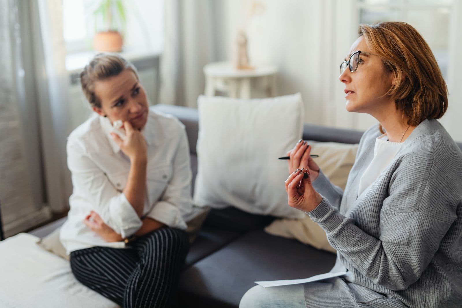 A therapist in conversation with a client on a sofa